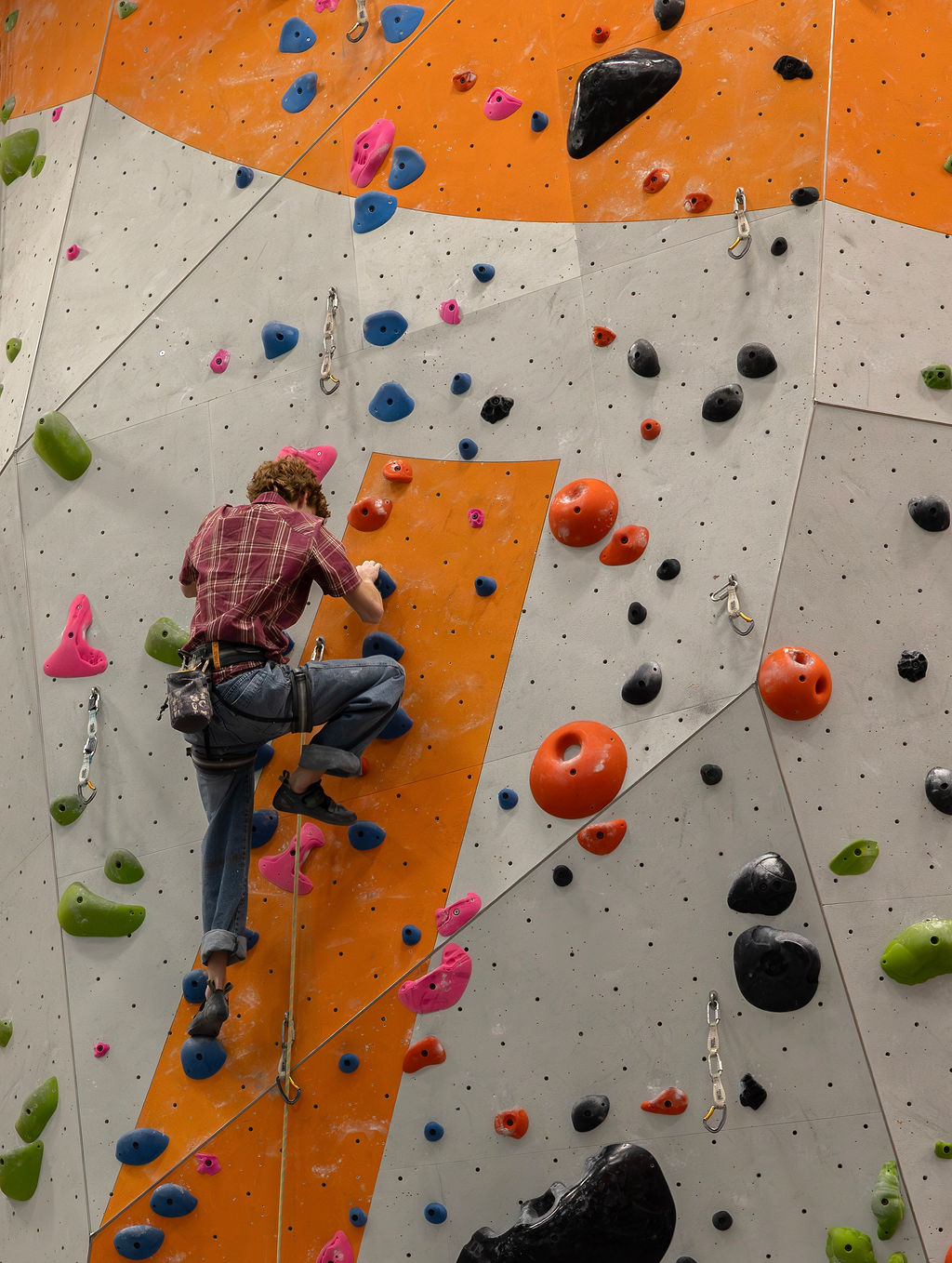 Cash high on the wall, seen from below, rope trailing beneath him